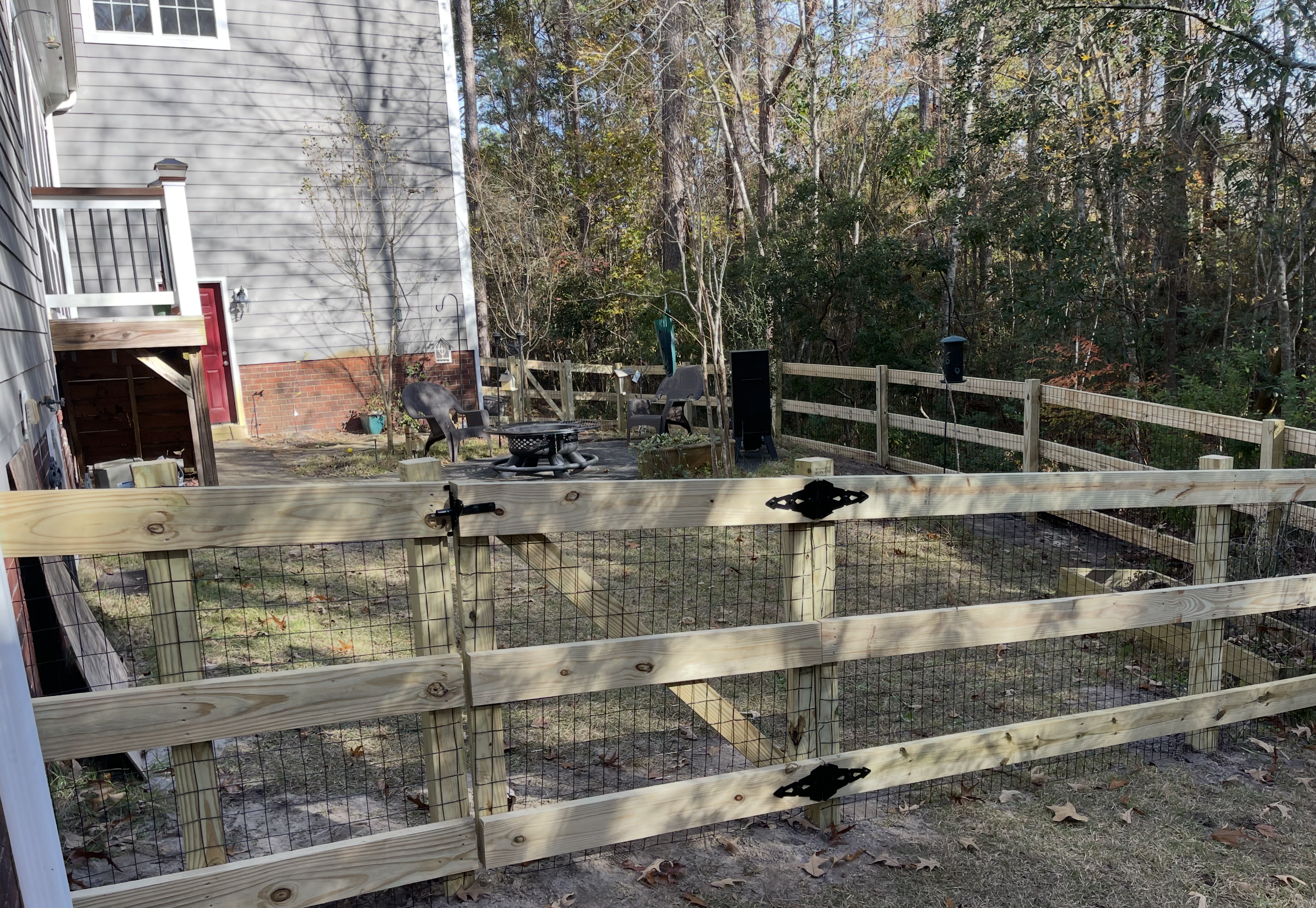 Four foot three-rail wood fence with wire mesh in Holly Ridge